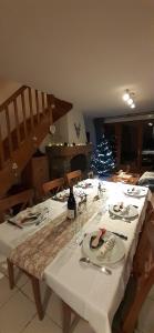 a table with a white table cloth and a christmas tree at Joli triplex 3 étoiles, avec jardin et cheminée in Génos +9 photos