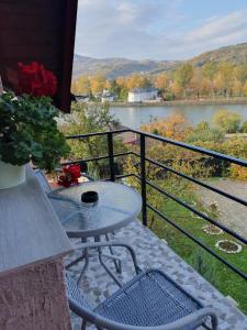 a table and chairs on a balcony with a view of a river at Casa Luci&Matei in Căciulata