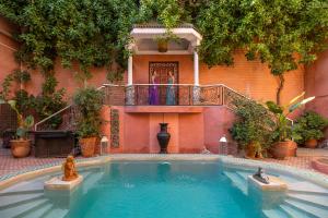 a swimming pool in front of a building with a balcony at Indian Palace in Marrakesh