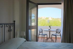 1 dormitorio con 1 cama, mesa y sillas en La Smeraldina Resort en Santa Teresa Gallura