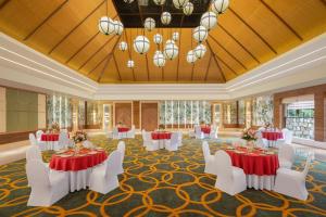 Ananta Spa & Resort, Pushkar في بوشكار: قاعة احتفالات مع طاولات وكراسي بيضاء وغرفة كبيرة