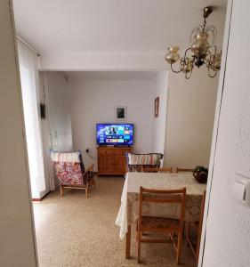 ein Wohnzimmer mit einem Tisch, Stühlen und einem TV in der Unterkunft 7楼下就是沙滩的好房子 in Santa Pola