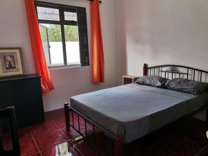 sypialnia z łóżkiem i oknem z pomarańczowymi zasłonami w obiekcie Villa TORARICA w mieście Pointe aux Biches