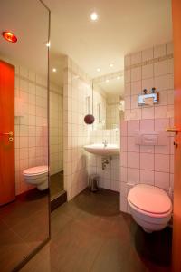 ein Badezimmer mit 2 WCs und einem Waschbecken in der Unterkunft Hotel Markkleeberger Hof in Markkleeberg