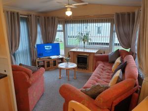 ein Wohnzimmer mit einem Sofa und einem TV in der Unterkunft 6 Berth Central heated on The Chase (Balmoral) in Ingoldmells