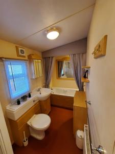 ein Badezimmer mit einem WC, einem Waschbecken und einer Badewanne in der Unterkunft 6 Berth Central heated on The Chase (Balmoral) in Ingoldmells