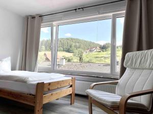 ein Schlafzimmer mit einem Bett und einem Stuhl sowie einem großen Fenster in der Unterkunft **Schwarzwald-Haus mit Sauna** in Elzach