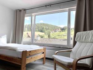 um quarto com uma cama e uma cadeira e uma grande janela em **Schwarzwald-Haus mit Sauna** em Elzach