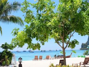 a beach with chairs and a tree and the ocean at Phi Phi Sand Sea View Resort in Phi Phi Islands
