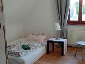 ein kleines Schlafzimmer mit einem Bett und einem Tisch mit einer Lampe in der Unterkunft Haus Scheibenhardt 