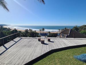 a wooden deck with benches and a view of the beach at THE ARK in Zinkwazi Beach in Zinkwazi Beach