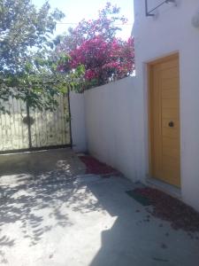 a fence with a door and a tree with pink flowers at Maison a louer a la grotte de Bizerte in Dar el Koudia