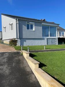 ein Haus mit Rasen und Auffahrt in der Unterkunft Plage du Débarquement. Maison bord de Mer in Saint-Côme-de-Fresné