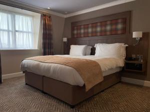 1 dormitorio con 1 cama grande con sábanas y almohadas blancas en Dillon’s Hotel, en Letterkenny