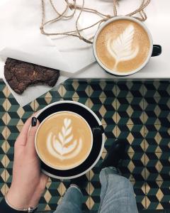 una persona sosteniendo dos tazas de café en una mesa en The Yarn, en Horgen