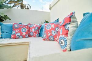 a white couch with blue and red pillows on it at The Hatua Peaceful Homeaway Haven in Arusha