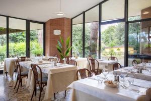 un restaurante con mesas, sillas y ventanas grandes en Hotel Venezia, en Marina di Pietrasanta