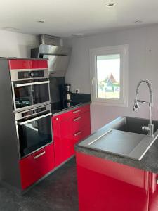 eine Küche mit roten Schränken und einer Spüle in der Unterkunft Plage du Débarquement. Maison bord de Mer in Saint-Côme-de-Fresné + 31 Fotos