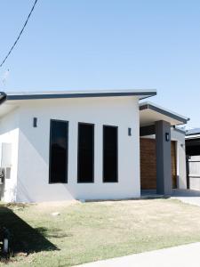 Une maison blanche aux fenêtres noires dans l'établissement New Home close to Airport hospital Coles & Resto, à Mackay