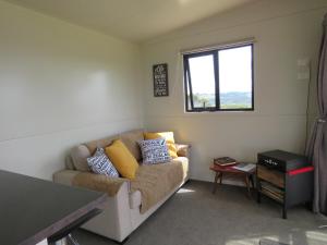 a living room with a couch and a window at Tuis Scenic Retreat in Cable Bay