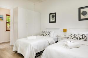 two beds in a white room with white walls at Constantia Oasis Petite in Cape Town
