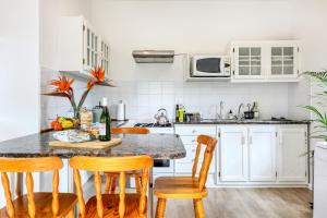 a kitchen with white cabinets and a table with chairs at Constantia Oasis Petite in Cape Town
