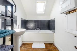 La salle de bains est pourvue d'une baignoire blanche et d'un lavabo. dans l'établissement L'appartement Casquette, à Liège