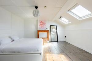 Schlafzimmer mit einem weißen Bett und Oberlichtern in der Unterkunft L'appartement Casquette in Lüttich