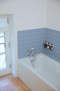 a bath tub in a bathroom with blue tiles at Magnifique maison proche de Paris, La Prairie by Oasis House in Égreville +22 photos