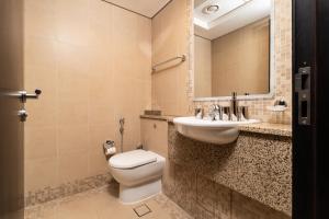 a bathroom with a toilet and a sink and a mirror at Nasma Luxury Stays - Elegant 1BR With Stunning View of Park Avenue in Dubai