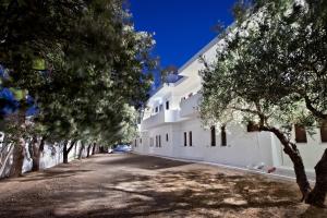 a white building with trees lining a road at Apartment with garden view - Creta in Ferma