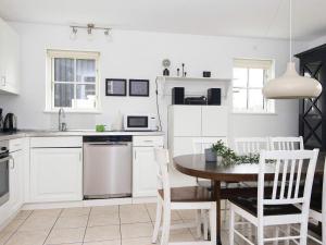 cocina con armarios blancos, mesa y sillas en 8 person holiday home in Gjern en Gjern