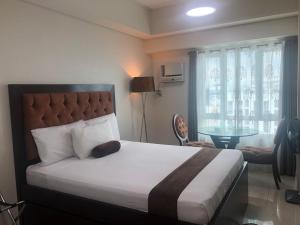 a bedroom with a large bed and a desk and a window at Studio Unit at The Beacon Makati in Manila