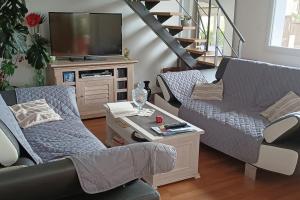 a living room with a couch and a tv at Au calme de la Poterie in Châteaubriant