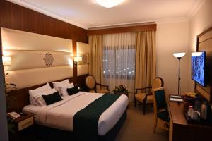 a hotel room with a bed and a desk and a television at One Inn Hotel in Medina