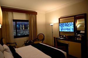 One Inn Hotel في المدينة المنورة: غرفة فندقية فيها سرير ومكتب وتلفزيون