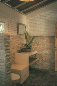 a bathroom with a toilet and a plant on the counter at Tamuku Padang Padang in Uluwatu
