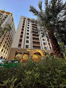 a tall building with a palm tree in front of it at One Inn Hotel in Al Madinah
