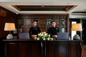 dos hombres parados detrás de un escritorio con dos portátiles en Paradise Elegance Cruise Halong, en Ha Long