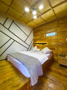 a bedroom with a bed in a room with wooden walls at Cabin Linggayoni dieng in Dieng