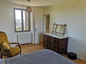 - une chambre avec un lit, un miroir et une chaise dans l'établissement Villa Thérèse, à Beaulieu-sur-Dordogne