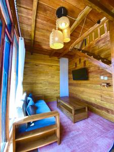 a room with a bed and a couch and a tv at Cabin Linggayoni dieng in Dieng