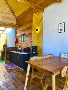 a dining room with a wooden table and a kitchen at Cabin Linggayoni dieng in Dieng