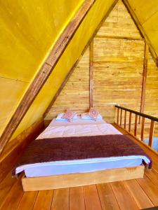 Bett in einem Holzzimmer im Dachgeschoss in der Unterkunft Cabin Linggayoni dieng in Diyeng