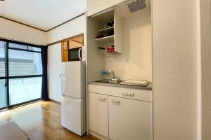a kitchen with a white refrigerator and a sink at Lavie Heights in Osaka