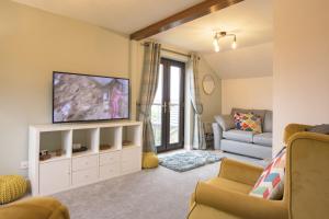 a living room with a tv and a couch at Oak Lodge House in Leyburn