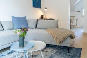 een woonkamer met een bank en een tafel met bloemen bij Apartment Blausand in Ahrenshoop