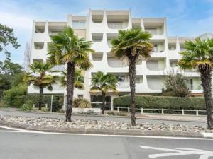 Un edificio blanco con palmeras delante. en Appartement Le Grain de Sable, en Saint-Palais-sur-Mer