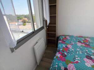 1 dormitorio con ventana y 1 cama con colcha de flores en Appartement Le Grain de Sable, en Saint-Palais-sur-Mer