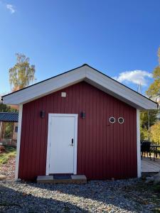 Un granero rojo con una puerta blanca. en Minihus i Enskede-Årsta-Vantörs en Estocolmo